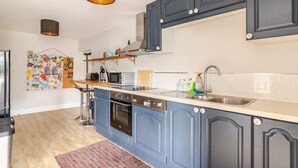 A modern kitchen with blue cabinets, a stainless steel sink, and a microwave.