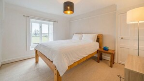 A bedroom with a bed, bedside table, lamp, and window.