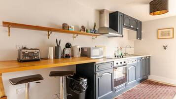 A compact kitchen with a wooden countertop, a toaster, a kettle, a microwave, and a sink.