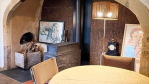 Un comedor acogedor con un arco de piedra rústico, una chimenea y una mesa dispuesta para dos.