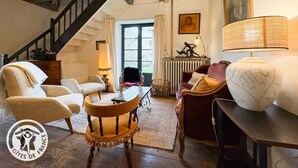 Un salón acogedor con escalera, muebles de mimbre, un radiador y una lámpara.