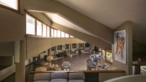 A spacious, modern interior with a curved ceiling, multiple seating areas, and large windows allowing natural light. - Holiday flat studio apartment with air conditioning (Castiglione della Pescaia)