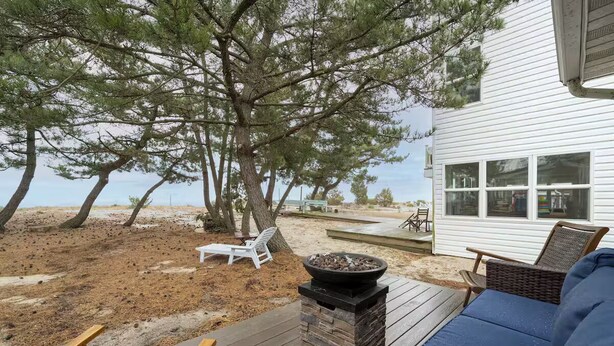 A deck with outdoor seating, a fire pit, and a view of the beach. - SEAJOY-Waterfront Rare Coastal Gem
Pet Friendly-fenced yard-Completely Renovated (Milford)