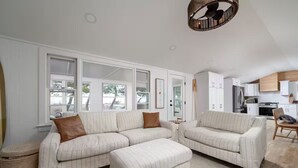 A modern living room with a large sectional sofa, ottoman, and a dining area with a wooden table and chairs. - SEAJOY-Waterfront Rare Coastal Gem
Pet Friendly-fenced yard-Completely Renovated (Milford)