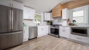A modern kitchen with white cabinetry, stainless steel appliances, and a wooden ceiling accent. - SEAJOY-Waterfront Rare Coastal Gem
Pet Friendly-fenced yard-Completely Renovated (Milford)