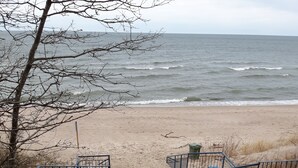 En träpromenad som leder till en sandstrand med bänkar och räcken.