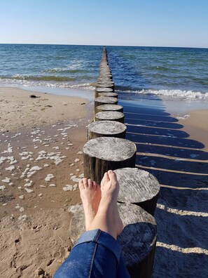 Eine hölzerne Steg, der ins Meer führt, mit Füßen darauf.