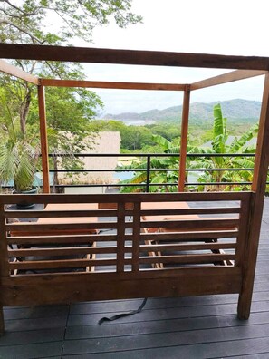Un banco de madera con vista a una piscina y abundante vegetación.