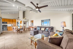 A spacious living area with a sectional sofa, a glass coffee table, and a dining area with wooden chairs and a table. A ceiling fan and pendant lights are visible. - 2 2 Luxurious Wailea Oceanview Resort Vistas (Wailea-Makena)