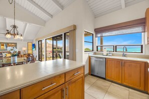 A spacious kitchen with wooden cabinets, a large island, and a view of the ocean. - 2 2 Luxurious Wailea Oceanview Resort Vistas (Wailea-Makena)