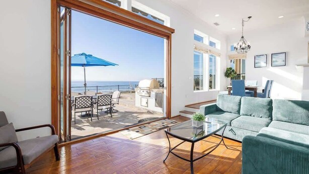 Een ruime woonkamer met een grote schuifpui naar een balkon met uitzicht op zee.