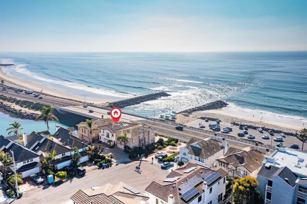 A coastal residential area with houses, a beach, and a road.