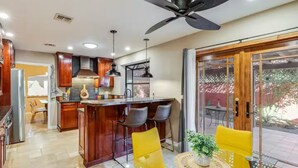 A modern kitchen with a central island, bar stools, and a dining area with yellow chairs. - A tranquil place to relax (Scottsdale)