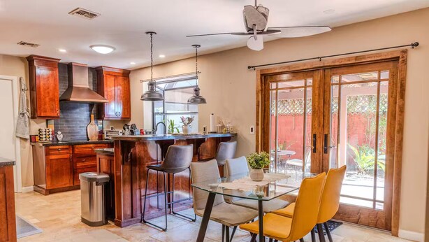 A kitchen with wooden cabinets, a stainless steel range hood, and a glass dining table with chairs. - A tranquil place to relax (Scottsdale)