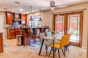 A kitchen with wooden cabinets, a stainless steel range hood, and a glass dining table with chairs. - A tranquil place to relax (Scottsdale)