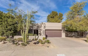 A modern two-story house with a garage, surrounded by desert landscaping including cacti and shrubs. - A tranquil place to relax (Scottsdale)