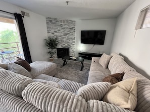 Una sala de estar con chimenea, un televisor de pantalla plana y un sofá.