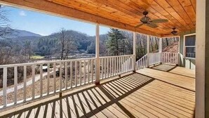 A wooden deck with a white railing, a ceiling fan, and a view of a forested valley. - The Nantahala Dollhouse
Cozy 3-bedroom rustic cottage in the heart of Nantahala (Topton)