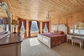A wooden-paneled room with a bed, dresser, and mirror.