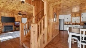 A wooden interior with a staircase, a fireplace, a dining area, and a kitchen. - The Nantahala Dollhouse
Cozy 3-bedroom rustic cottage in the heart of Nantahala (Topton)