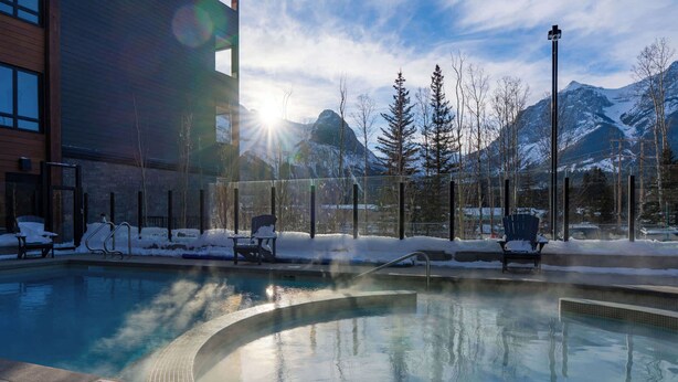 Piscina com espreguiçadeiras e vista para montanhas cobertas de neve.