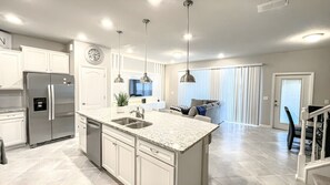A modern kitchen with a central island, stainless steel appliances, and pendant lighting. - 7545 OS - Solterra Resort Grandeur Luxurious 5-Bedroom Pool Home (Davenport)