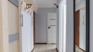 Un corridoio con una porta in legno, una porta bianca e uno specchio a destra.