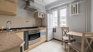 Una cucina moderna con forno integrato, microonde e lavello. È presente una zona pranzo con tavolo e sedie in legno.