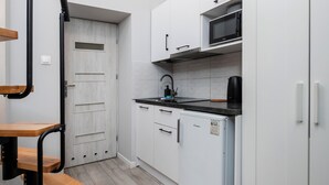 Una cocina pequeña con armarios blancos, un microondas, un fregadero y un refrigerador.