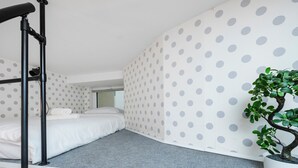 Habitación pequeña con literas, una mesita y una planta en maceta.