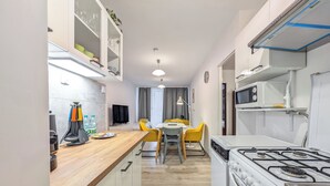 Uma cozinha moderna com fogão, micro-ondas e área de refeições com cadeiras amarelas.