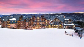 Een groot hotel met meerdere gebouwen, een skilift en een besneeerd landschap.