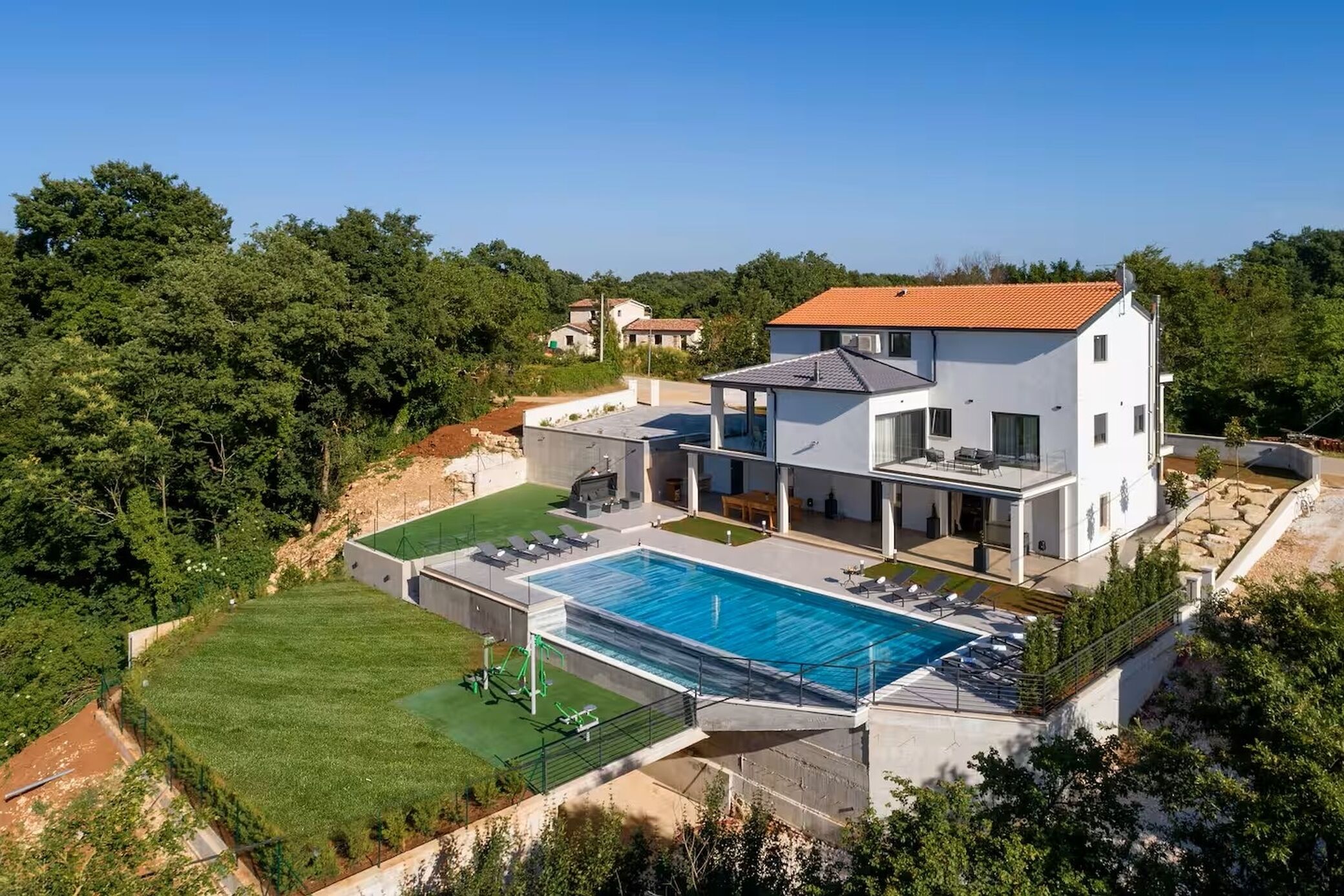 A modern two-story house with a swimming pool, a covered patio, and a well-maintained lawn.
