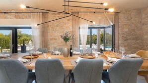 Ein Essbereich mit Steinwand, modernen Stühlen und einem für eine Mahlzeit gedecktem Tisch.