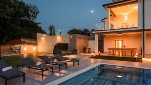 Ein modernes Haus mit Pool, Sitzgelegenheit im Freien und Grillbereich.