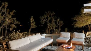 Een terras met een bank, stoelen en een vuurkorf.