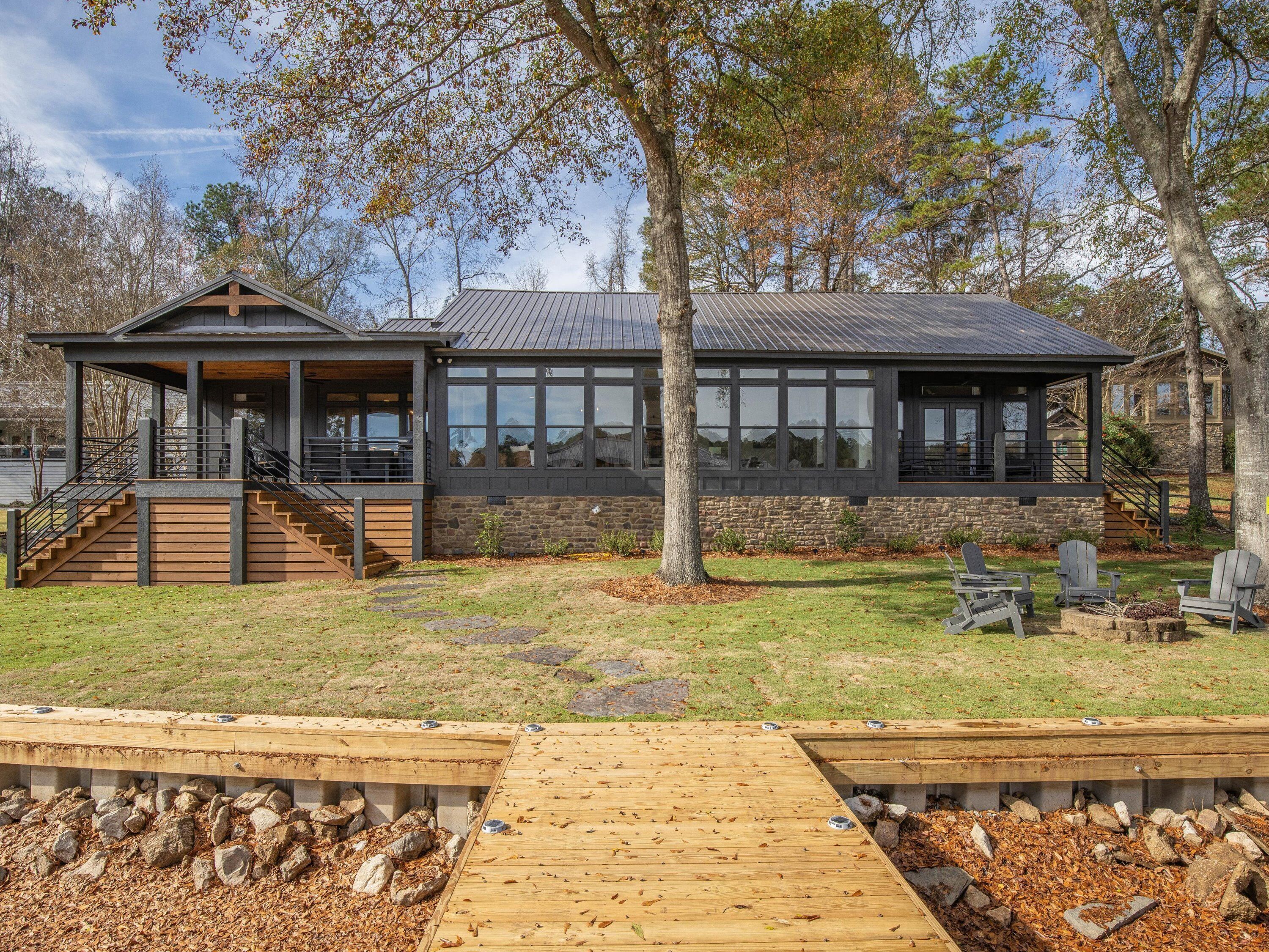 A modern house with a stone facade, large windows, and a wooden deck.