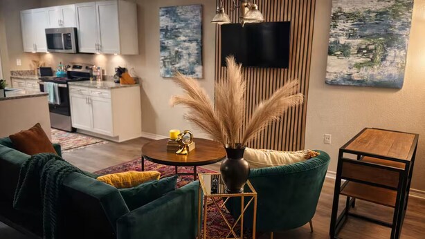 Una sala de estar moderna con un sofá verde, una mesa de centro redonda y una mesita auxiliar de madera.