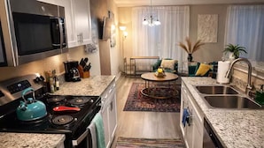 Una cocina moderna con electrodomésticos de acero inoxidable, encimera de granito y una isla central.