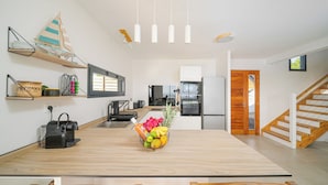 A modern kitchen with a wooden island, a fruit bowl, and a sailboat decoration. - Villa Mansfenil - Le Marin- Sea and forest view (Le Marin)