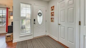 A hallway with a white door, a window with blinds, and a doormat. - Grill Patio • Pet Friendly • 3BR (Charlotte)
