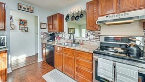 A modern kitchen with wooden cabinets, a stainless steel stove, and a dishwasher. - Grill Patio • Pet Friendly • 3BR (Charlotte)