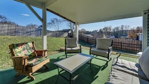 A covered patio with a wooden bench, two chairs, and a small table. - Grill Patio • Pet Friendly • 3BR (Charlotte)