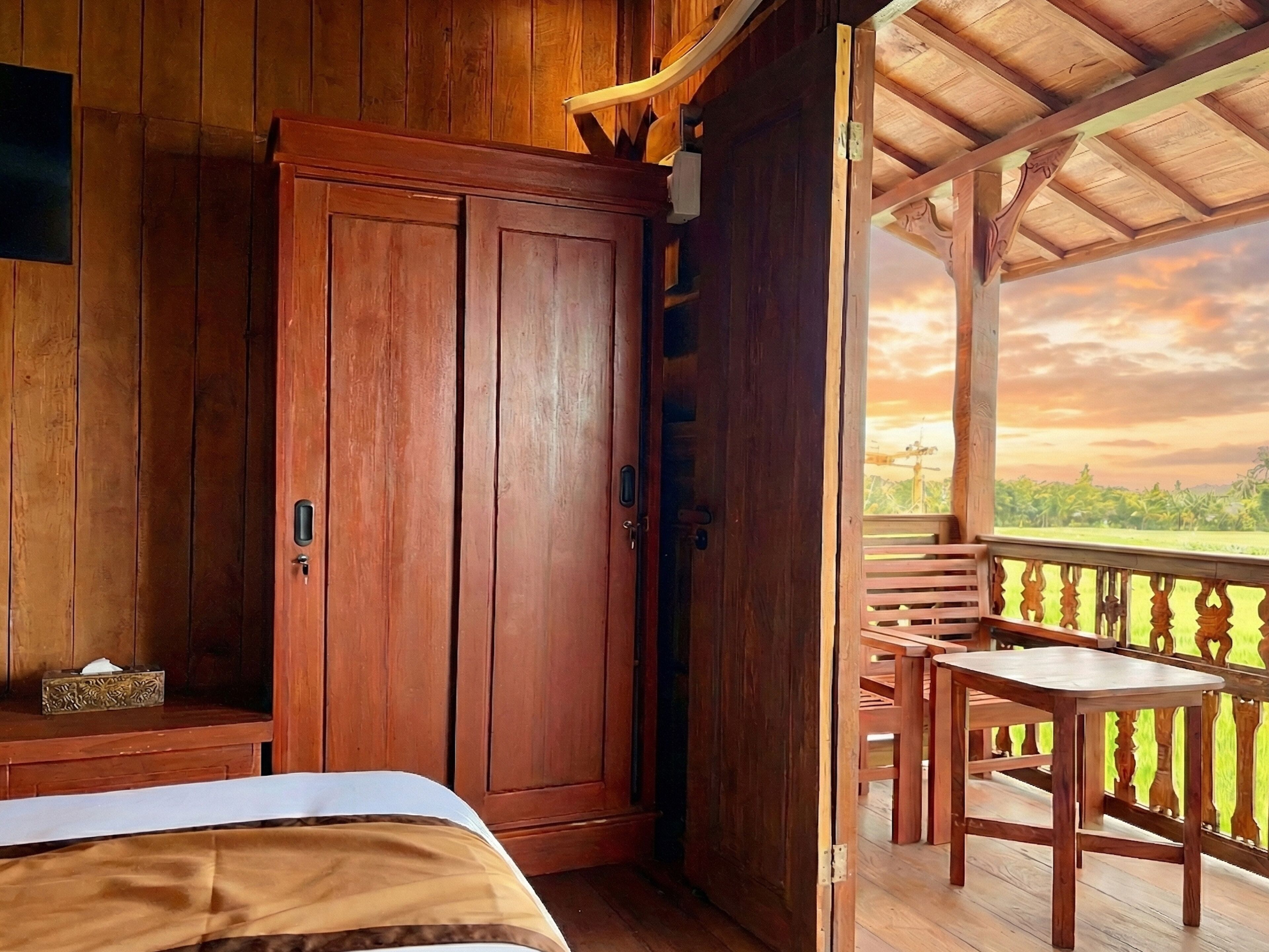 Een houten kamer met een bed, een kledingkast en een balkon met uitzicht op het landschap.