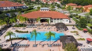 Ett semesterparadis med en swimmingpool, palmer och en byggnad med rött tak.