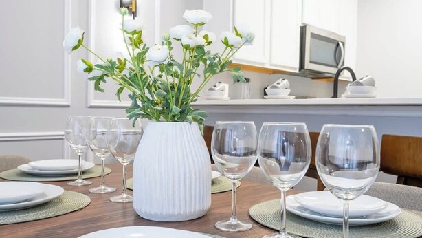 Ett matbord dukat med tallrikar, vinglas och en vas med blommor.