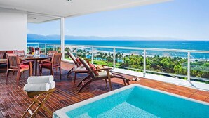 Ein Balkon mit Pool, Holzterrasse und Tisch mit Stühlen.