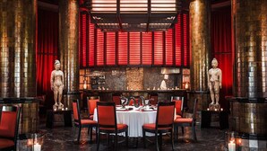 Ein Restaurant mit runden Tischen, roten Stühlen und Statuen.