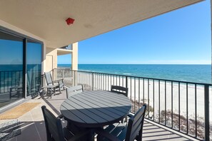 A balcony with a table and chairs, overlooking a beach and the ocean. - Beachfront Escape | Gulf-View Balcony, Resort Pools & Iconic Location | BEACHBALL PROPERTIES (Orange Beach)