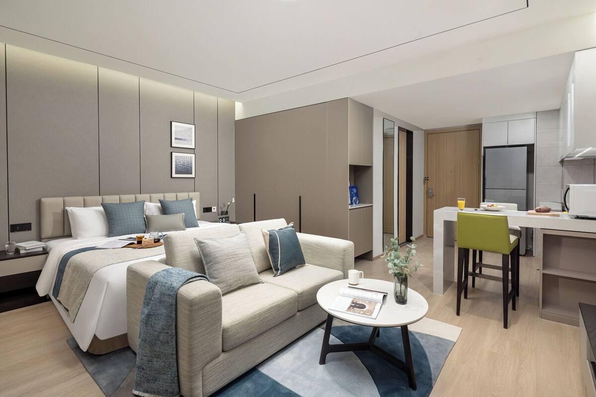 Une chambre d’hôtel moderne équipée d’un lit, d’un canapé, d’une table à manger et d’un coin cuisine.